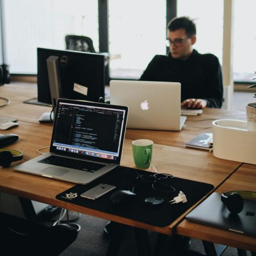 A web developer working on code in a modern office setting with multiple devices.